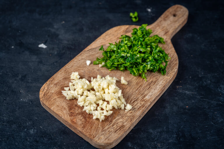 Mincing garlic and parsley for squid in tomato sauce
