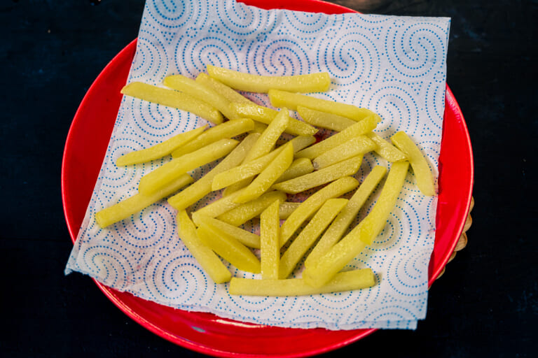 Partially cooked french fries being transferred to paper towels