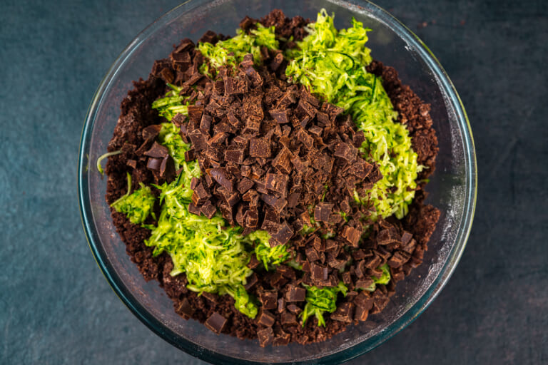 Grated zucchini and chopped chocolate in a bowl with ingredients Grated zucchini and chopped chocolate in a bowl with ingredients