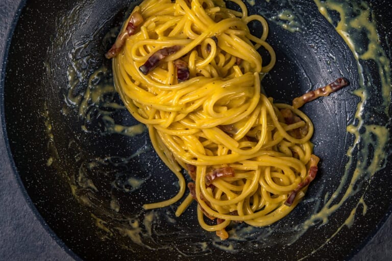 Guanciale pieces with spaghetti in the pan