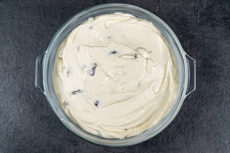 Farmer's cheese and raisin batter poured into a prepared baking dish.
