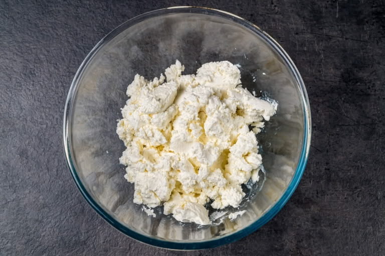 Farmer's cheese in a mixing bowl, ready to be prepared for the Zapekanka batter.