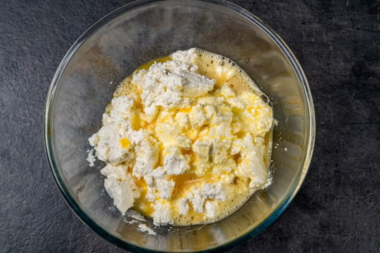 Whisked eggs being mixed into farmer's cheese for a smooth Zapekanka base.