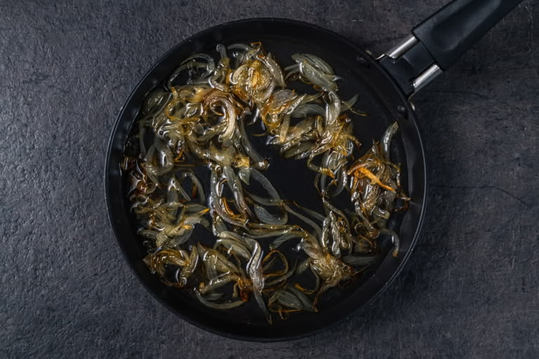Coarsely chopped onion frying until golden in vegetable oil in a skillet to flavor the oil.