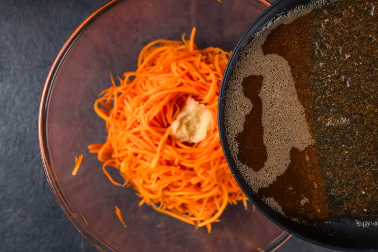 Ground coriander, black pepper, and cayenne pepper being added to hot, onion-infused oil in a skillet.
