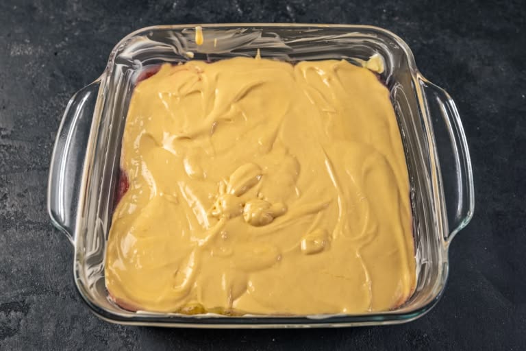The cake batter being poured over the layer of caramelized rhubarb in the baking pan.