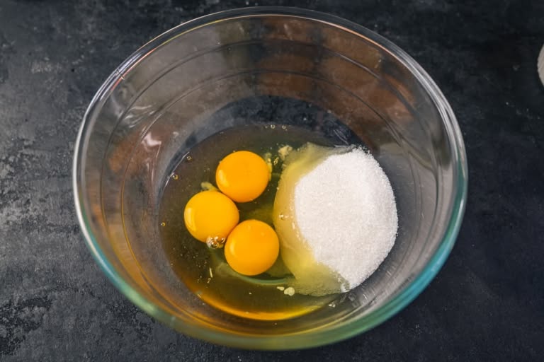 Eggs and sugar in a glass bowl.