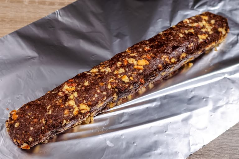 The chocolate salami mixture placed on a sheet of aluminum foil, ready to be shaped into a log.