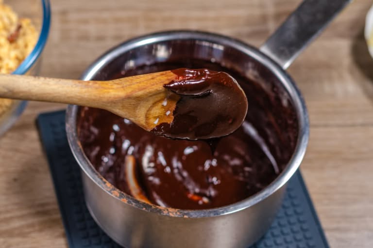 Heating the chocolate, sugar, and milk mixture in a saucepan, stirring with a spatula until smooth.