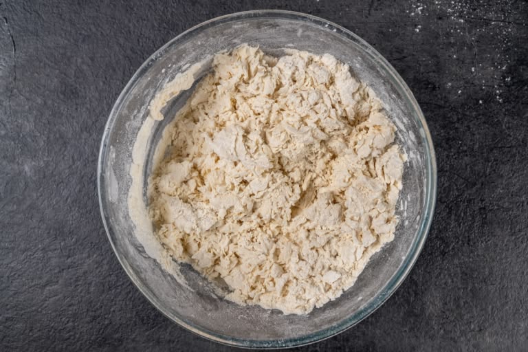 Mixing flour and water to create a shaggy pelmeni dough