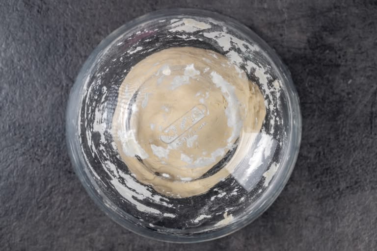 Smooth, elastic ball of pelmeni dough resting under a bowl
