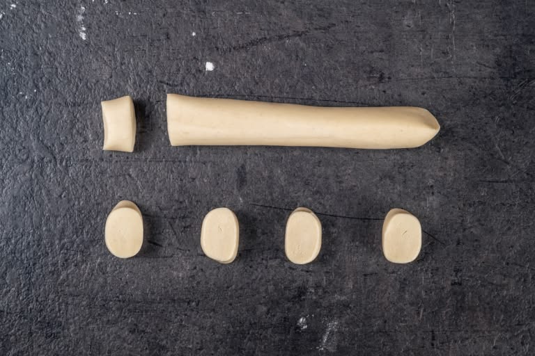 Rolling pelmeni dough into a long rope and cutting into small pieces