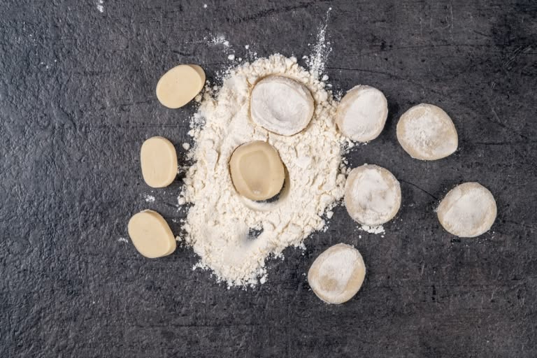 Pressing and rolling small dough pieces into thin rounds for pelmeni