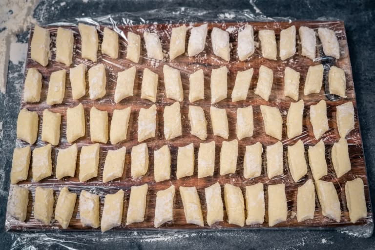 Raw, diamond-shaped lazy vareniki arranged on a floured board.