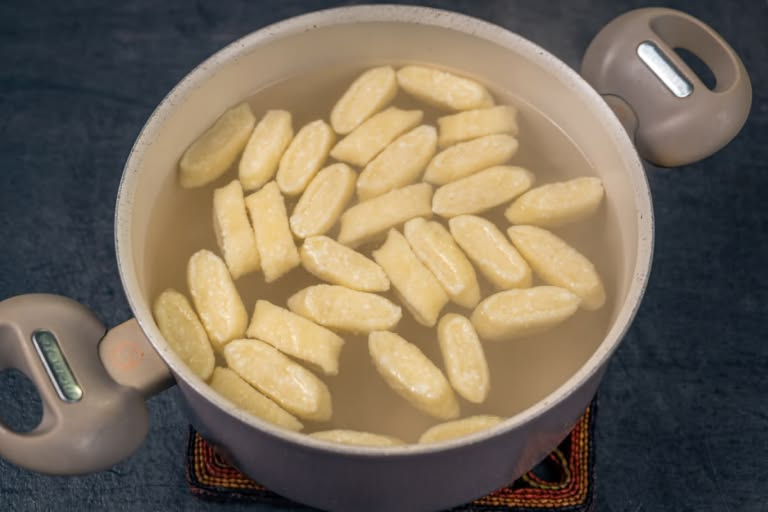 Dropping the raw lazy vareniki into a pot of boiling water.