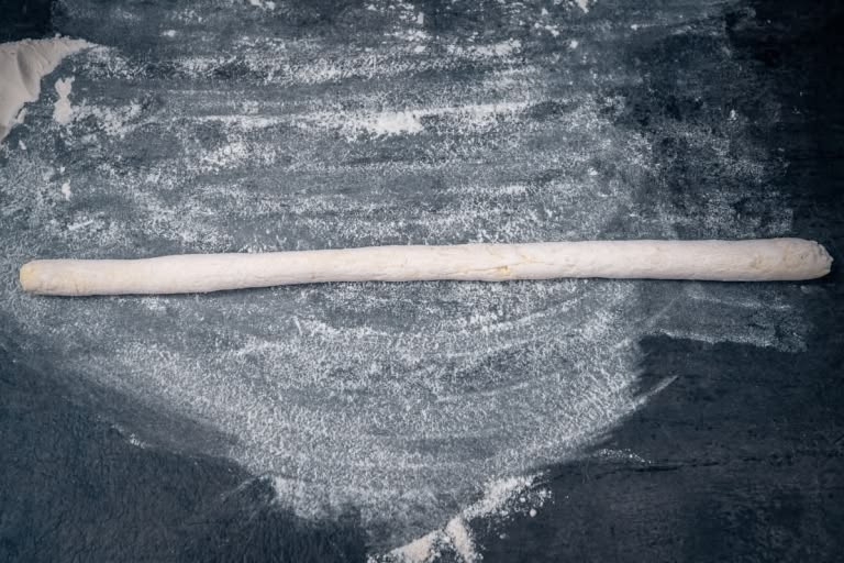 Rolling the soft dough into an even rope about 3/4 inch thick.