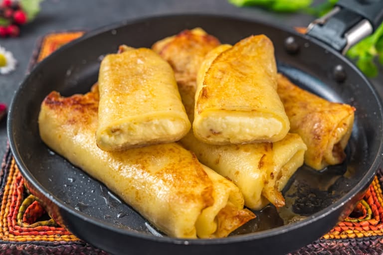 A plate of warm, golden-brown Ukrainian sweet cheese blintzes (nalysnyky)
