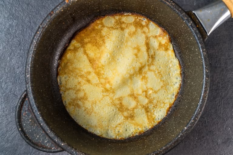 Cooking a thin milk crepe in a hot skillet over medium-high heat