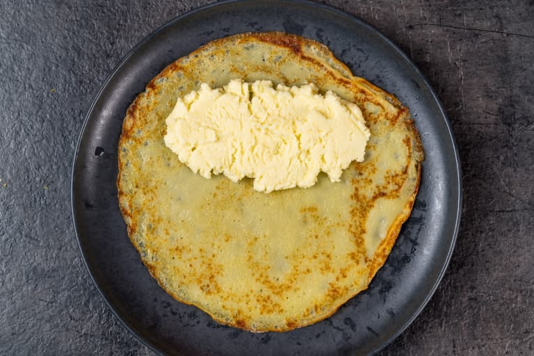 Spreading 2 to 3 teaspoons of sweet cheese filling on a cooked crepe